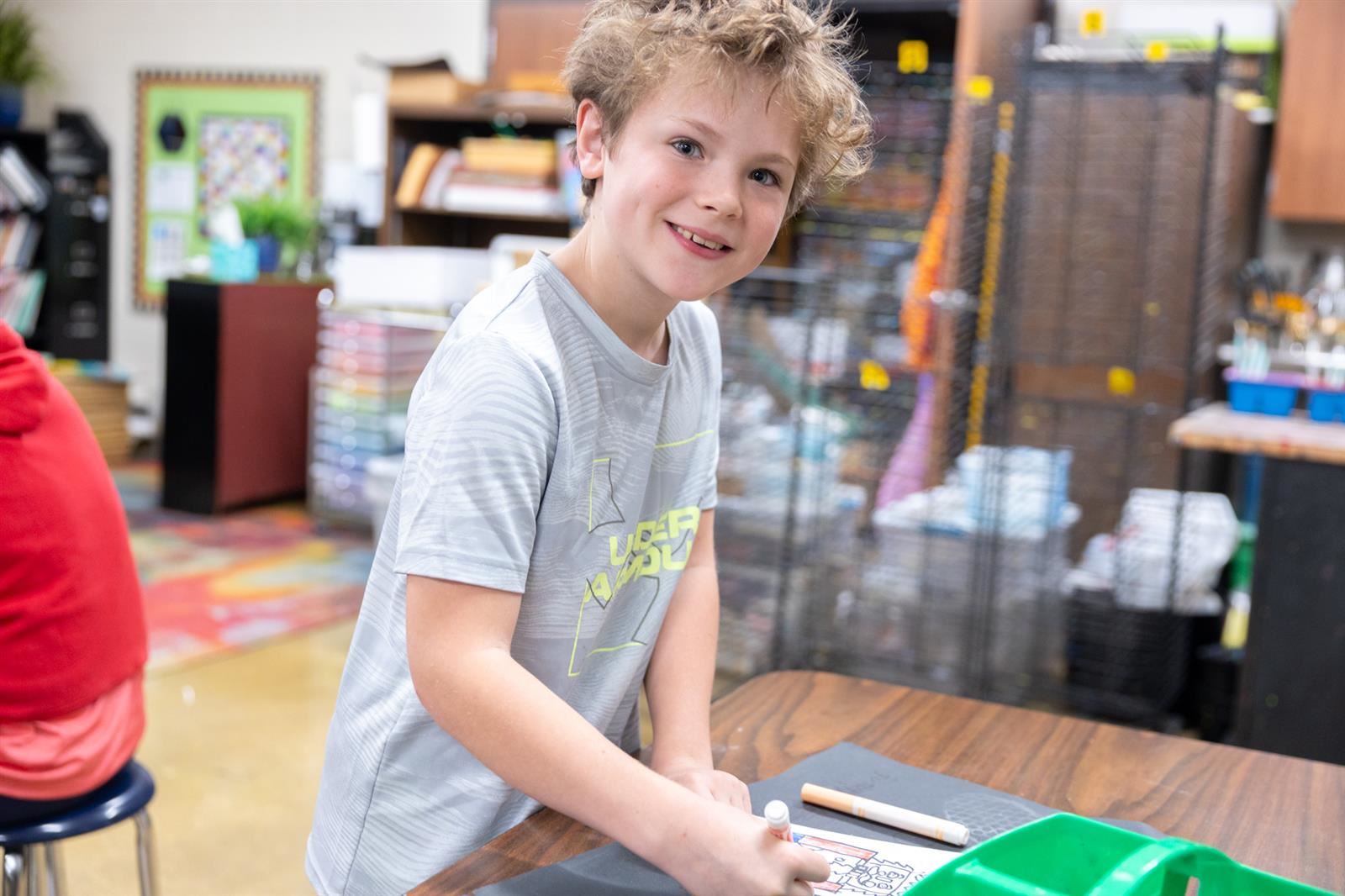 boy smiling while gluing